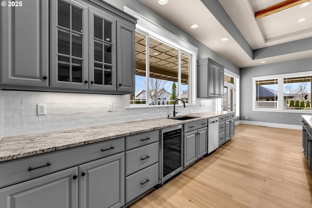 kitchen with wine cooler, gray cabinetry, a sink, baseboards, and decorative backsplash