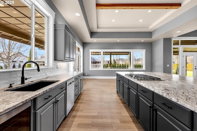 kitchen with wine cooler, stainless steel appliances, a raised ceiling, backsplash, and a sink