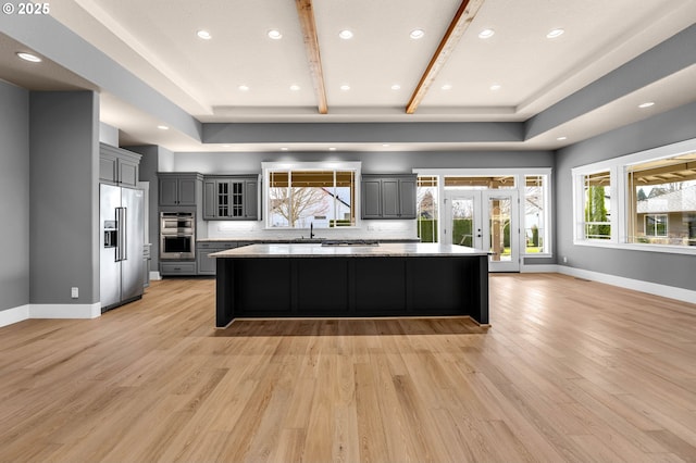 kitchen featuring stainless steel appliances, a spacious island, light wood-type flooring, and gray cabinets