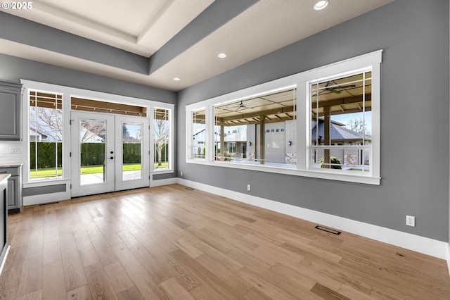 unfurnished living room featuring french doors, light wood-type flooring, visible vents, and baseboards