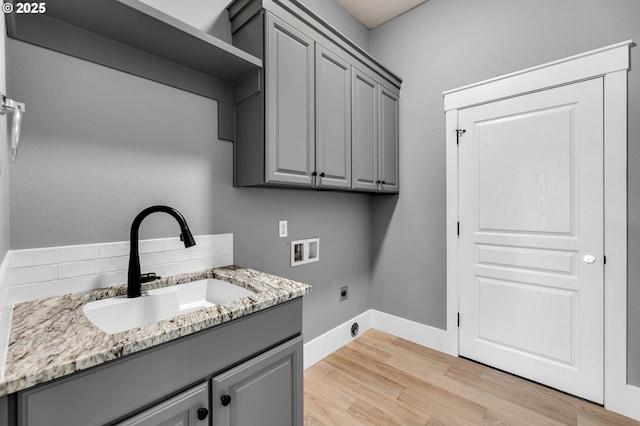 laundry room featuring cabinet space, light wood-style flooring, electric dryer hookup, washer hookup, and a sink