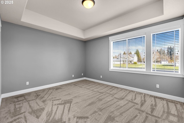 unfurnished room featuring baseboards and a raised ceiling