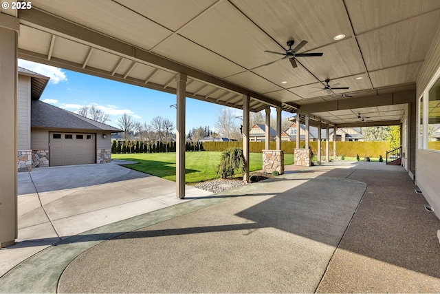 view of patio / terrace featuring an attached garage, a ceiling fan, and concrete driveway