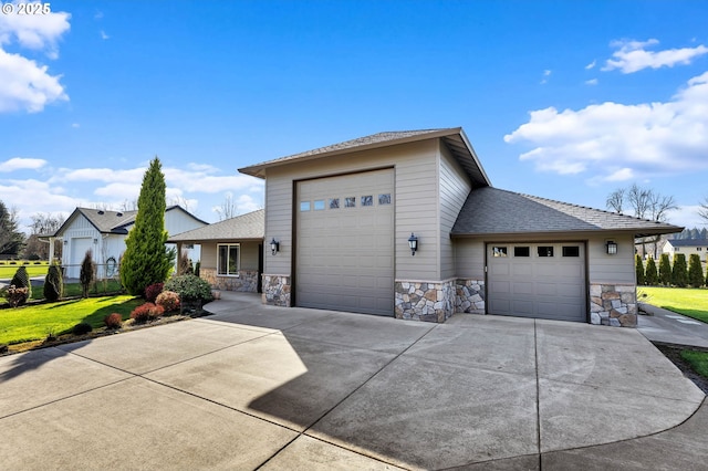 prairie-style house featuring concrete driveway, stone siding, an attached garage, fence, and a front yard