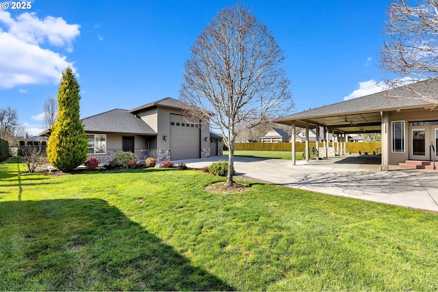 view of yard with a garage, fence, and concrete driveway