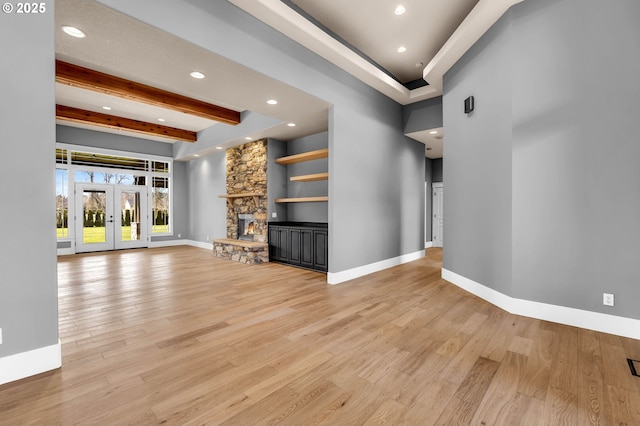 unfurnished living room featuring french doors, a fireplace, light wood-style flooring, and baseboards