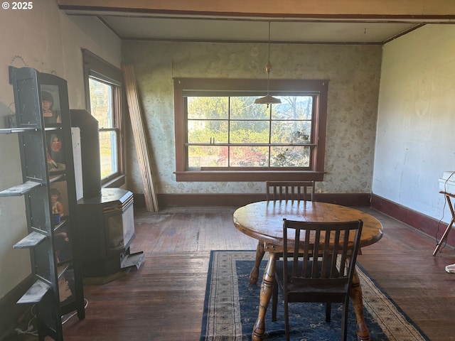 dining space featuring a wood stove, hardwood / wood-style floors, and baseboards
