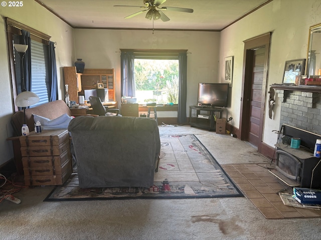 living room featuring a wood stove, carpet flooring, a ceiling fan, and crown molding
