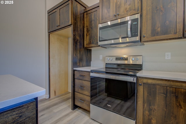 113 Citation Ct, Winston, OR 97496 - kitchen featuring stainless steel appliances, light countertops, light wood-type flooring, dark brown cabinetry, and baseboards