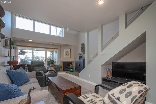 living room featuring a towering ceiling and light wood-type flooring