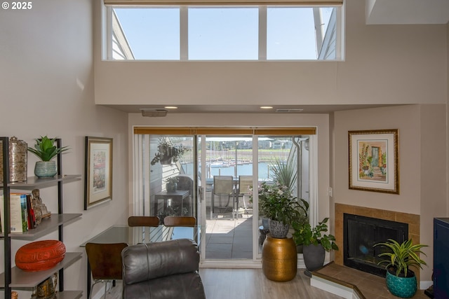 doorway to outside with a towering ceiling, a fireplace, a water view, and hardwood / wood-style flooring