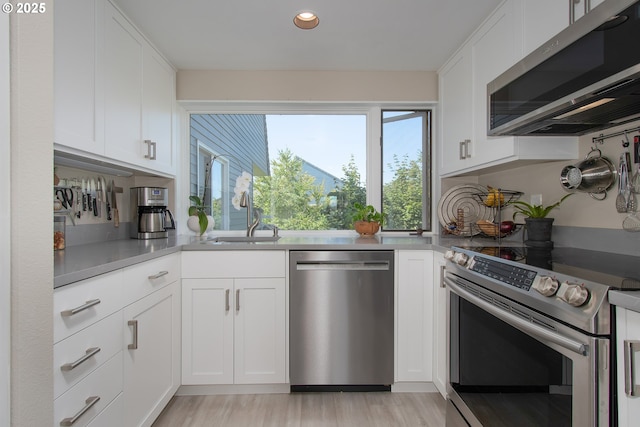 kitchen with white cabinetry, sink, stainless steel appliances, and light hardwood / wood-style floors