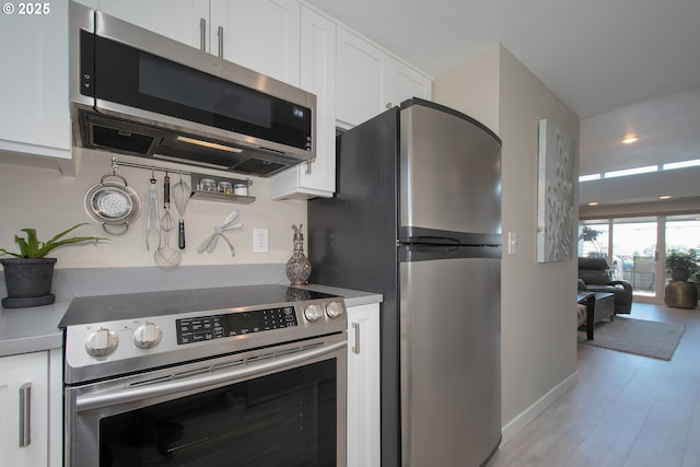 kitchen with white cabinets, stainless steel appliances, and light hardwood / wood-style flooring