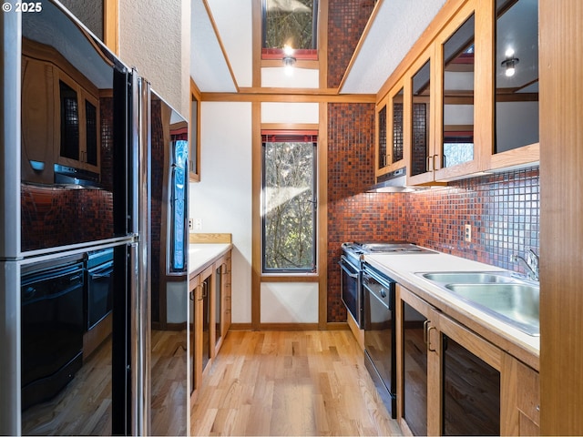 kitchen with dishwasher, sink, backsplash, and light hardwood / wood-style floors