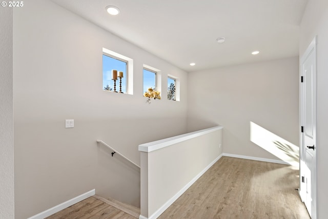 hall with recessed lighting, wood finished floors, baseboards, and an upstairs landing