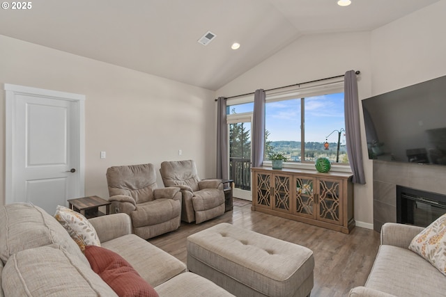 living room featuring vaulted ceiling, visible vents, recessed lighting, wood finished floors, and a fireplace