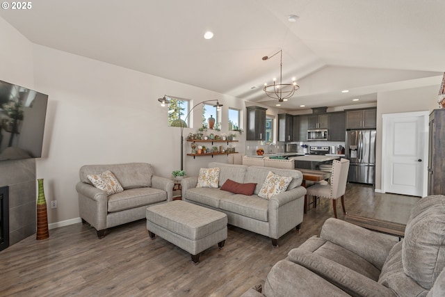 living area featuring lofted ceiling, a chandelier, dark wood-type flooring, and a fireplace