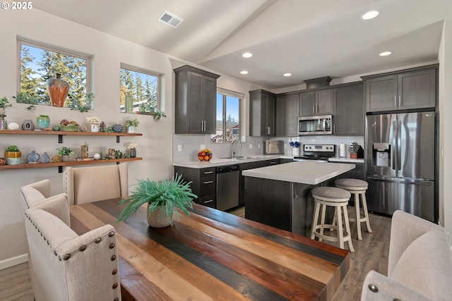 kitchen with lofted ceiling, light countertops, backsplash, visible vents, and appliances with stainless steel finishes