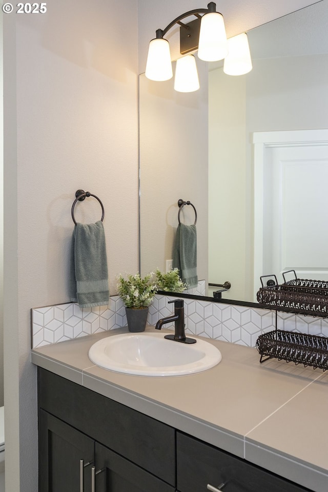bathroom with toilet, vanity, and tasteful backsplash