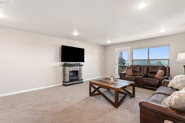 living room with baseboards, light carpet, a stone fireplace, and recessed lighting