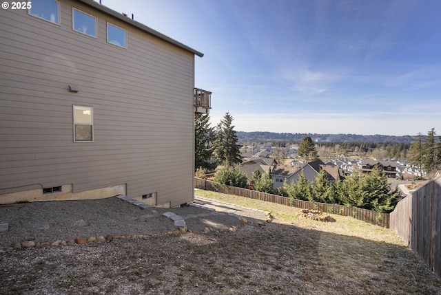 view of side of home featuring a residential view, a fenced backyard, and a balcony