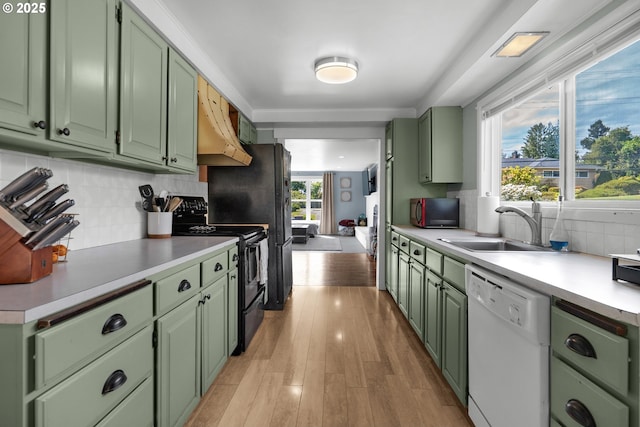 1858 5th St, Astoria, OR 97103 - kitchen with green cabinets, black appliances, under cabinet range hood, light countertops, and tasteful backsplash