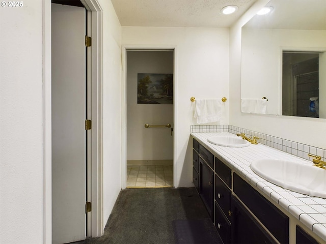 full bathroom featuring double vanity, a sink, and baseboards