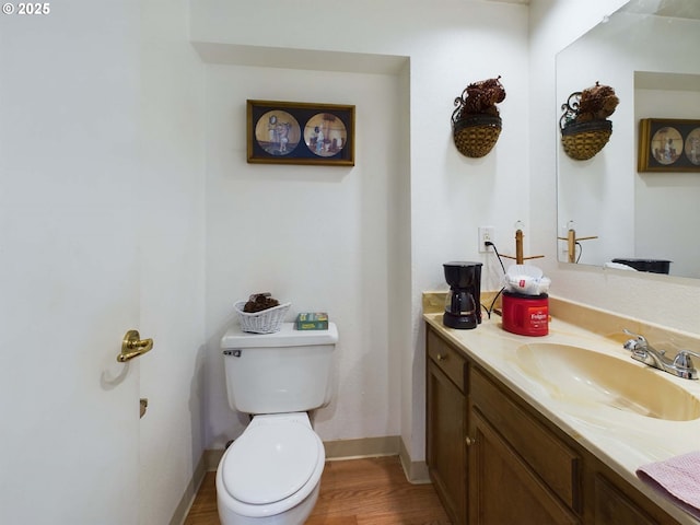 bathroom with toilet, baseboards, wood finished floors, and vanity