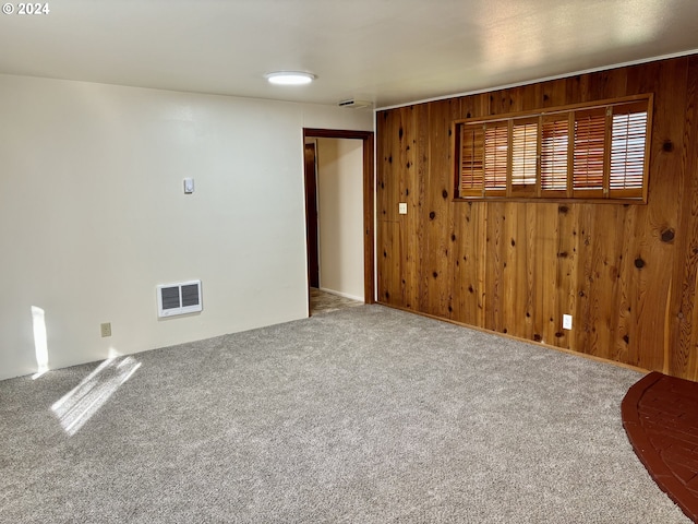 carpeted empty room featuring wooden walls