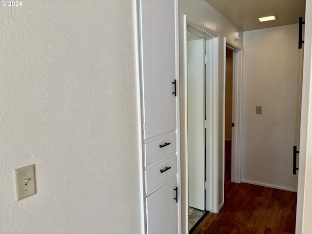 hallway featuring a barn door and dark hardwood / wood-style flooring