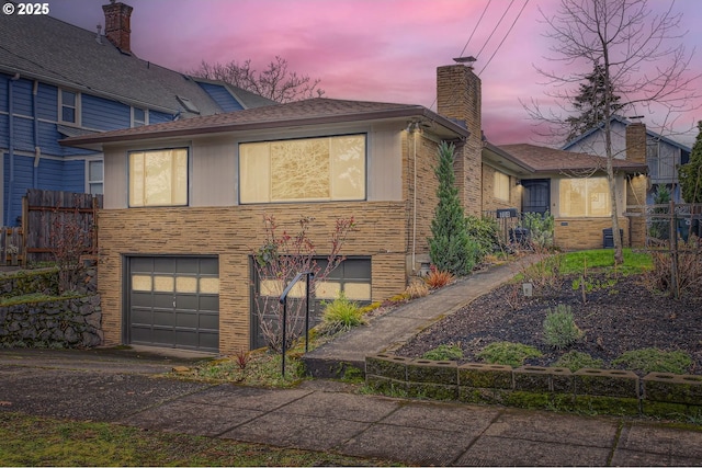 view of front of house featuring an attached garage, fence, driveway, and a chimney