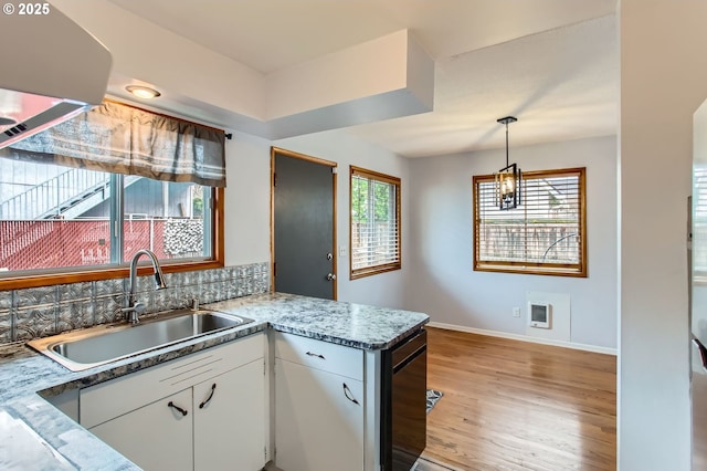 kitchen with a sink, heating unit, light wood-style floors, a peninsula, and white cabinets