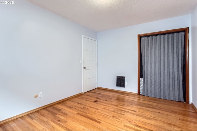 unfurnished bedroom featuring baseboards, a textured ceiling, and light wood-style flooring