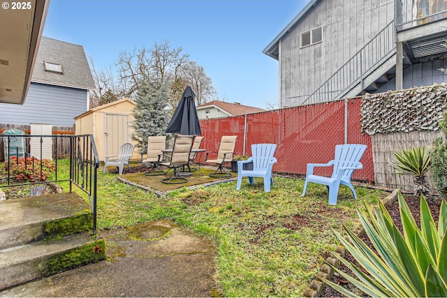 view of yard with an outdoor structure, a fenced backyard, a shed, and a patio area