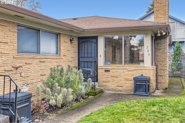 view of exterior entry with roof with shingles