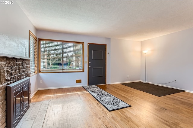 entryway featuring a glass covered fireplace, a textured ceiling, baseboards, and wood-type flooring