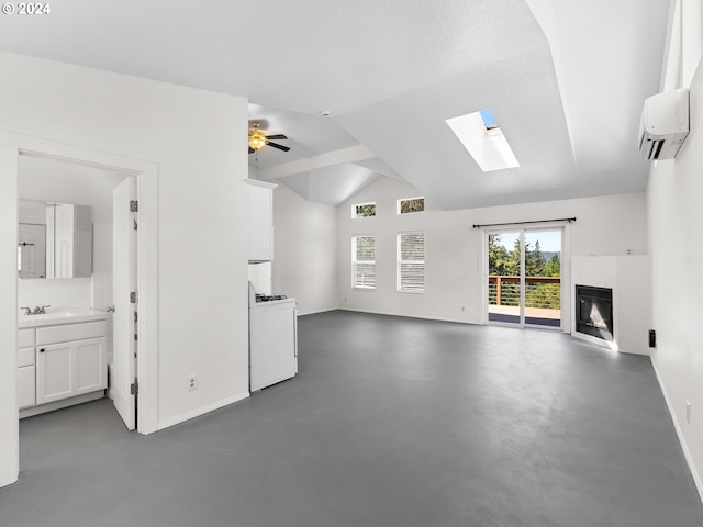 unfurnished living room with sink, lofted ceiling with skylight, an AC wall unit, and ceiling fan