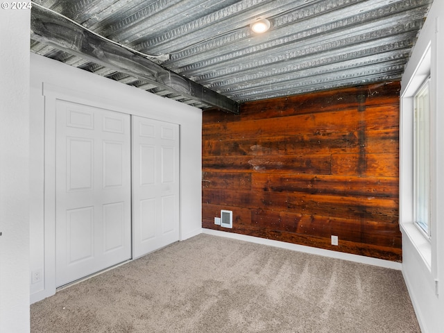 interior space with carpet flooring, a closet, and wood walls