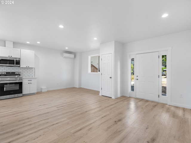 unfurnished living room featuring a wall mounted AC and light hardwood / wood-style flooring