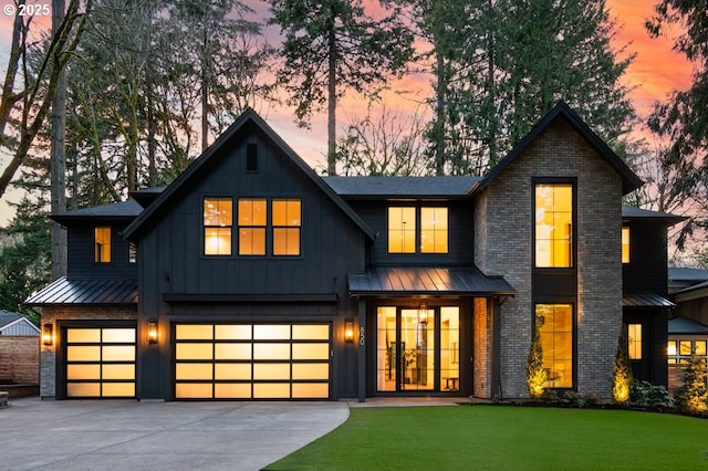 view of front of home featuring driveway, a garage, a standing seam roof, a front lawn, and board and batten siding