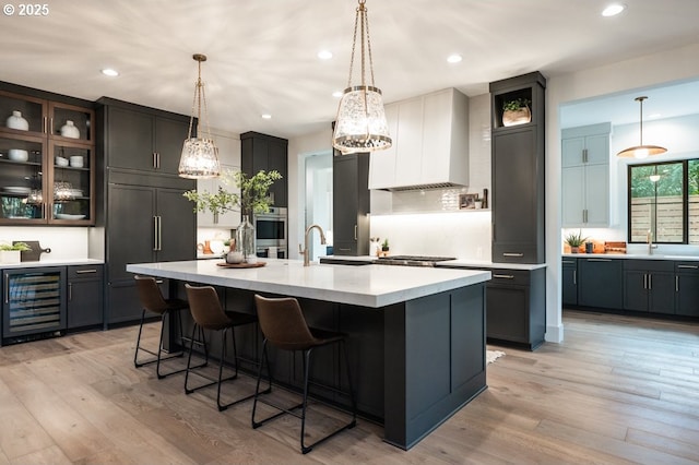 kitchen featuring light wood-type flooring, wall chimney range hood, beverage cooler, and paneled fridge