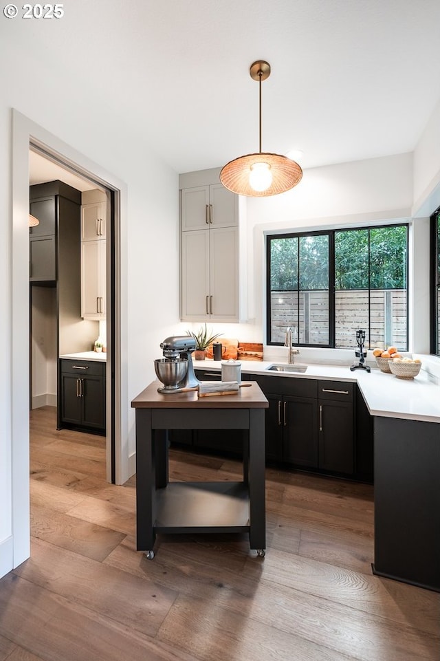 kitchen with light wood-style floors, light countertops, a sink, and decorative light fixtures