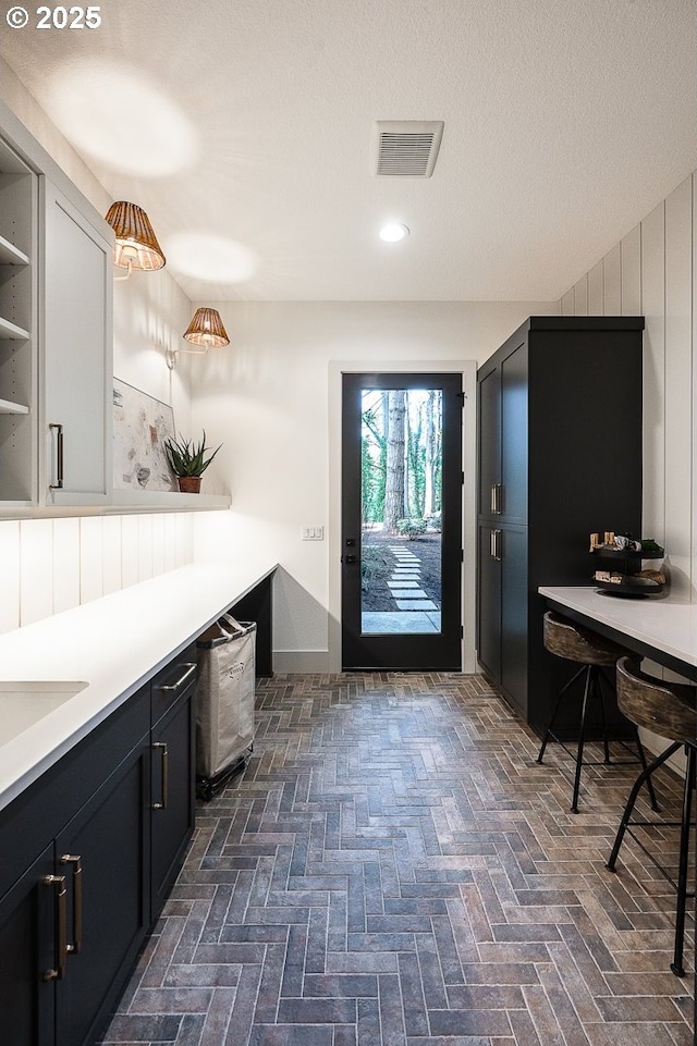 interior space featuring brick floor, visible vents, a textured ceiling, and recessed lighting