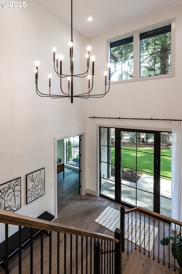 foyer with a notable chandelier, a high ceiling, wood finished floors, and recessed lighting