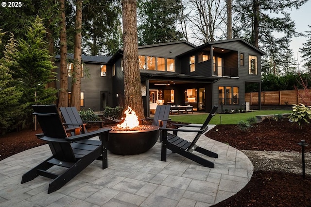 rear view of house with an outdoor fire pit, a patio area, fence, and a balcony