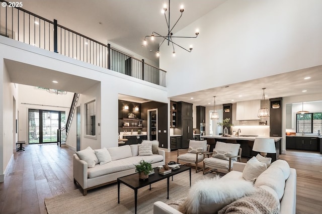 living area featuring light wood finished floors, recessed lighting, an inviting chandelier, and french doors