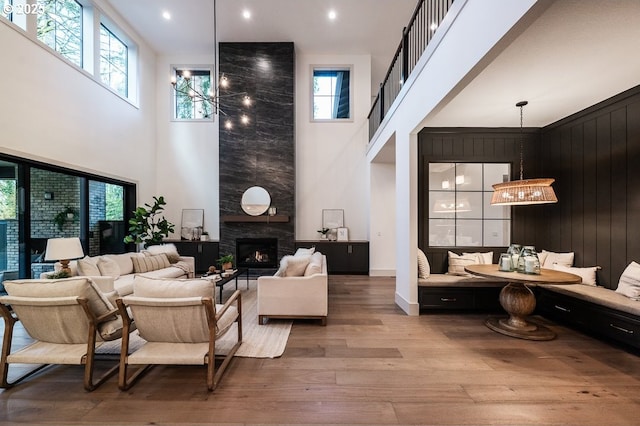 living room with wood finished floors, a tile fireplace, a towering ceiling, and an inviting chandelier