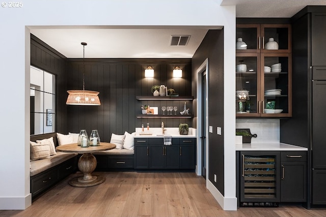 bar with light wood-style floors, wine cooler, and bar area