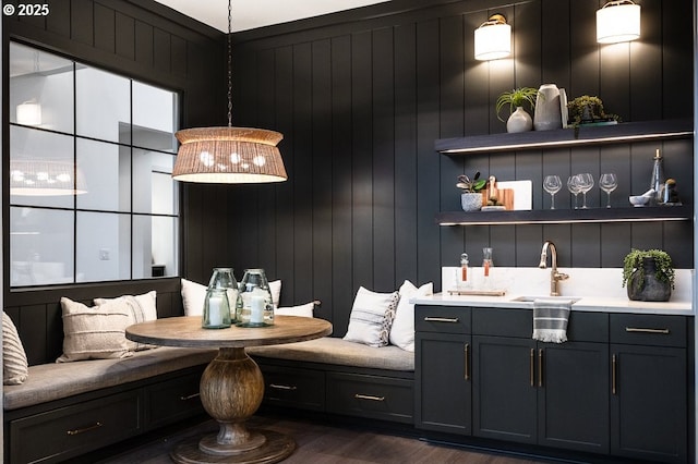 bar featuring dark wood-type flooring, a sink, and pendant lighting