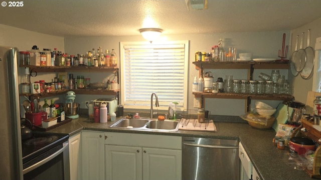 kitchen featuring stainless steel appliances, white cabinetry, sink, and a textured ceiling